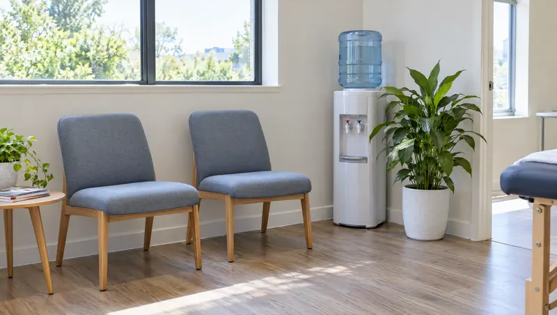 Waiting area with two armchairs, a water cooler and a plant by the window